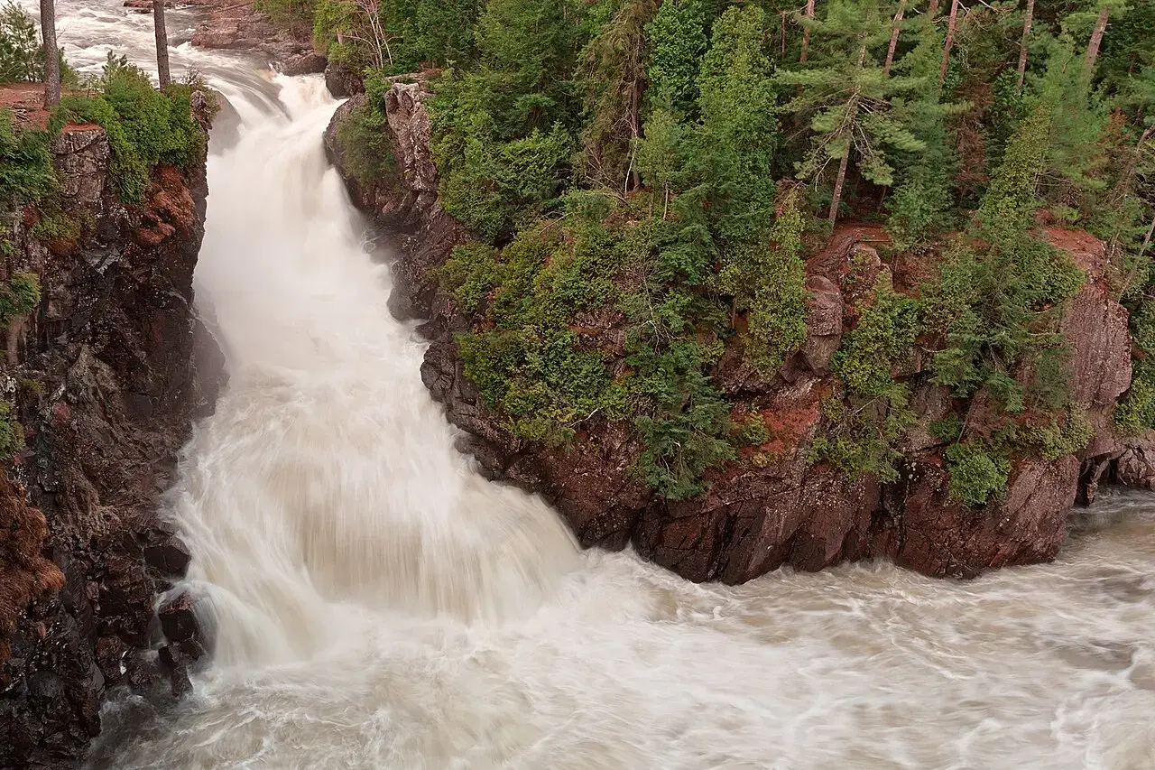 Dorwin Falls flowing between wooded rock cliffs.